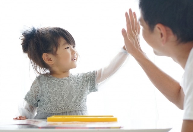 やったね！とハイタッチする子どもと保育士