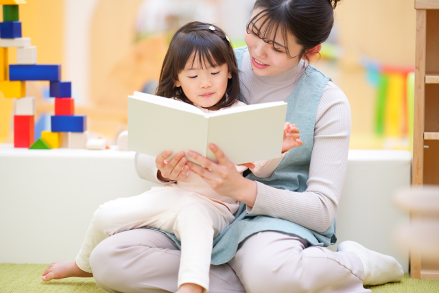 絵本を女の子に読んであげる女性保育士