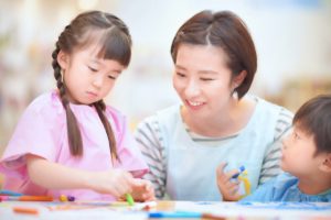 お絵描きする保育士とこども