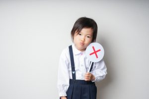 ×の札をもつ女の子