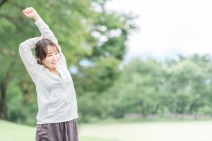 リフレッシュ　緑の中でストレッチする女性