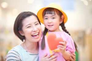 保育士と子どもが笑顔でハート型を持つ