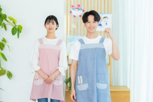 エプロン姿の男性保育士と女性保育士　自信に満ち溢れた笑顔