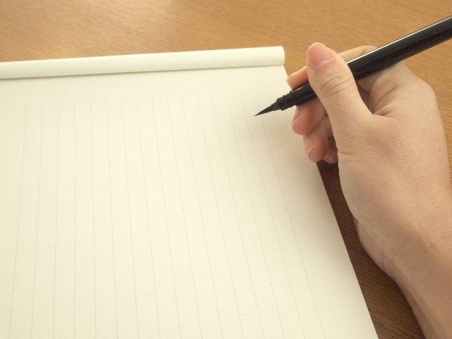 縦書きの便箋にペンで書こうとしている手元