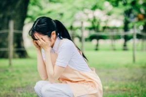 エプロン姿の保育士　座り込んで泣く　つらい