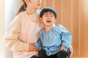 保育士の膝に座って泣く子ども