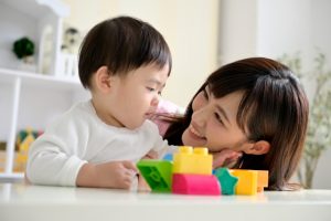 1歳児と保育士がブロックで遊ぶ